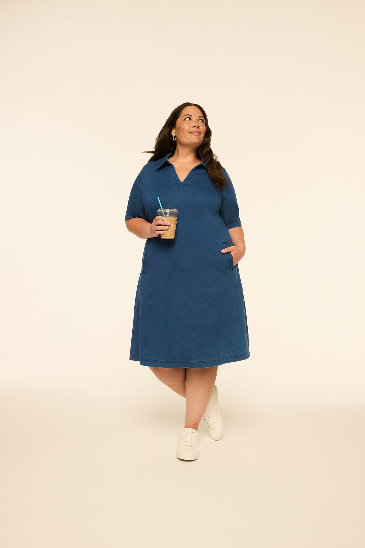 A woman in a blue dress holds a coffee cup while standing against a plain, light-colored background. Product Image 6