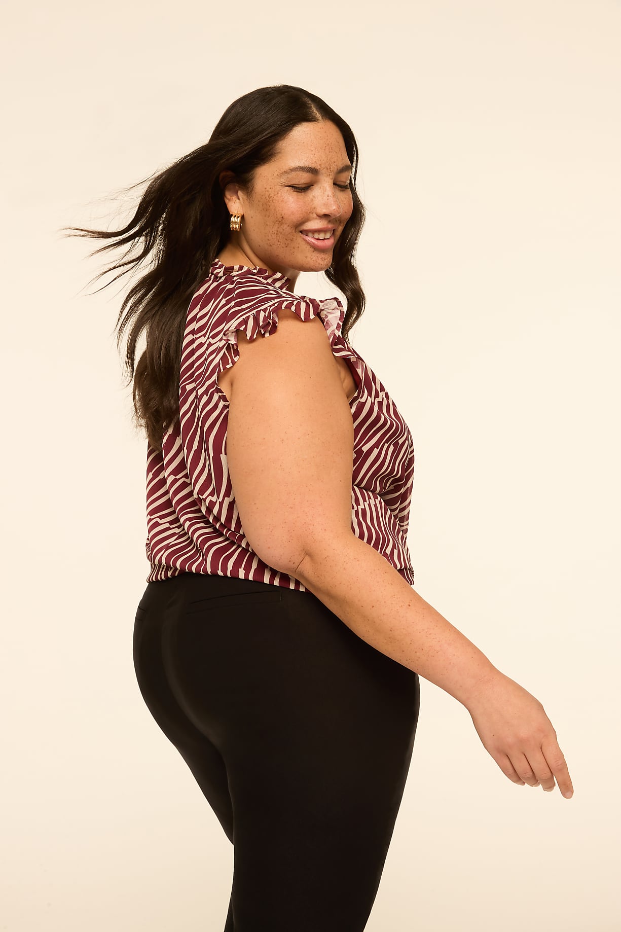 A woman with dark hair and a zebra-print top stands against a plain, light-colored background. Product Image 9