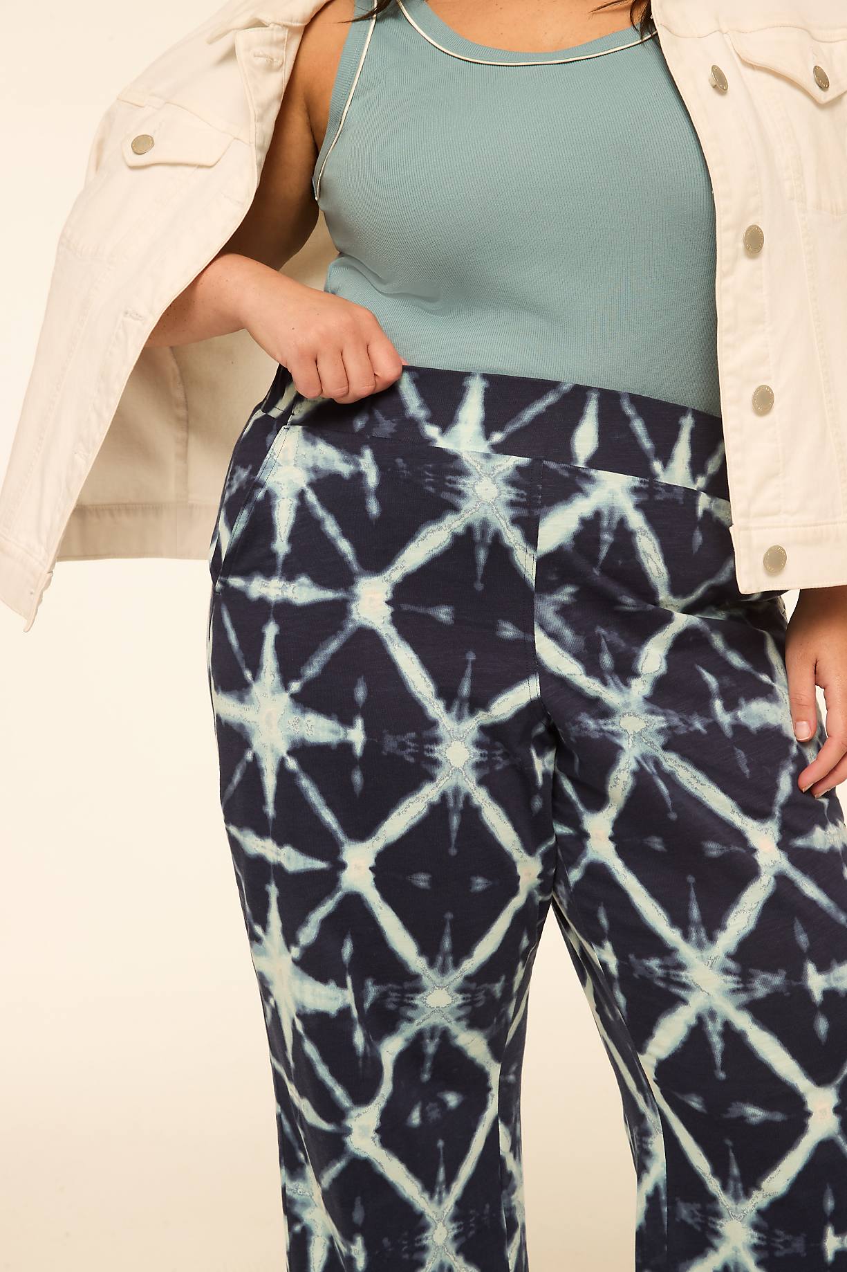 A person in a light jacket and a teal tank top wears dark blue tie-dye pants against a plain, light background. Product Image 8