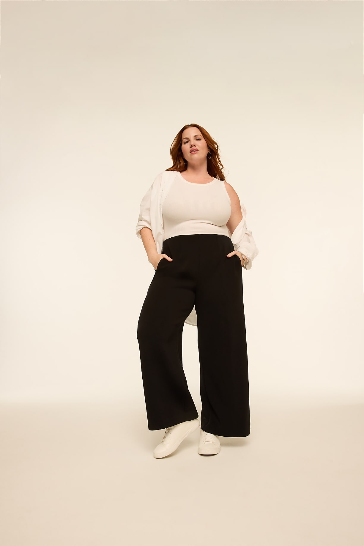 A woman in a white tank top, open white shirt, and black wide-leg pants stands with her hands in her pockets against a plain, light-colored background. Product Image 5