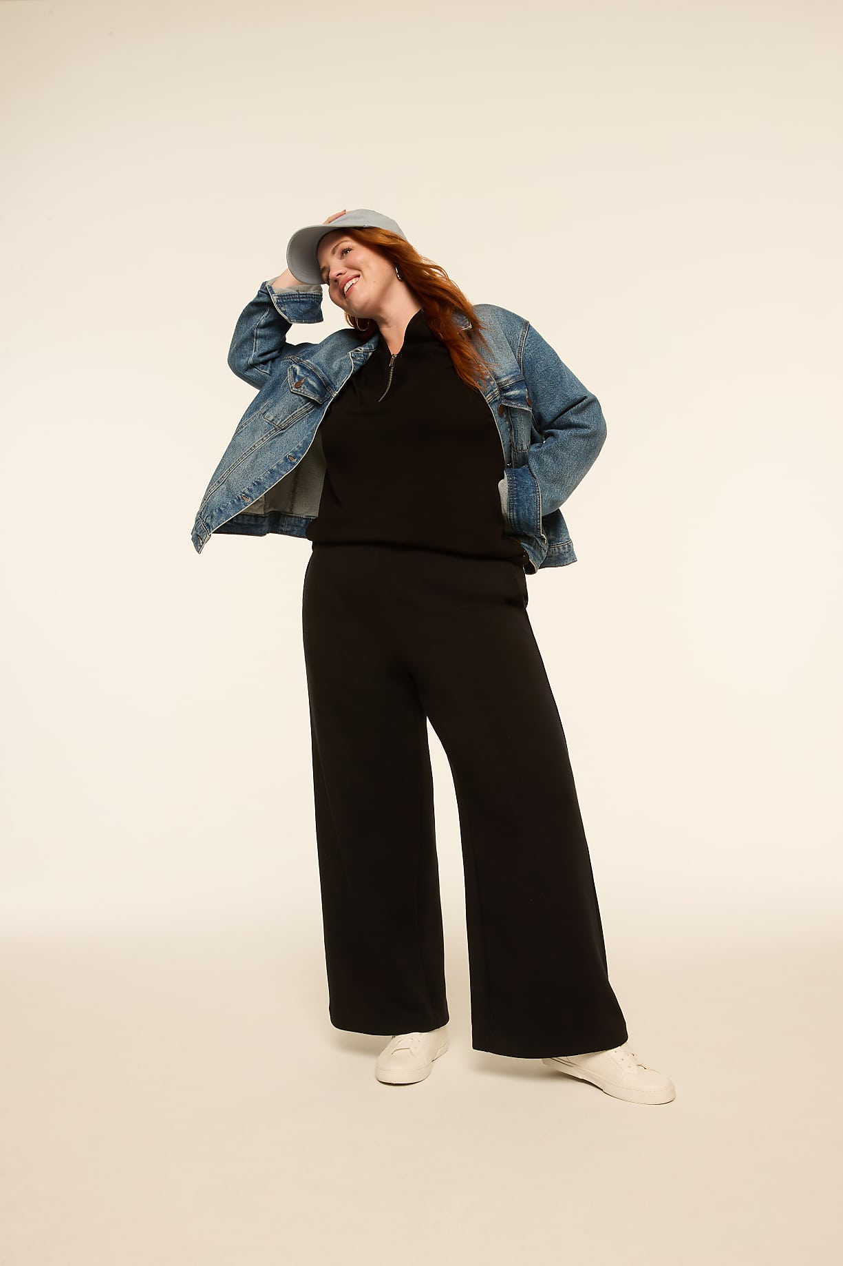 A woman in a black outfit and denim jacket poses with a light-colored background. Product Image 12