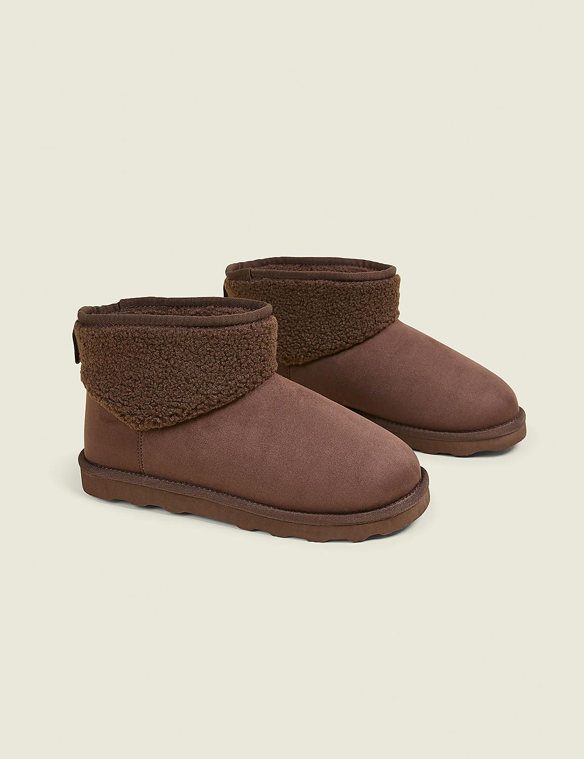 A pair of brown, fuzzy-lined ankle boots rests on a plain, light brown background. Product Image 1