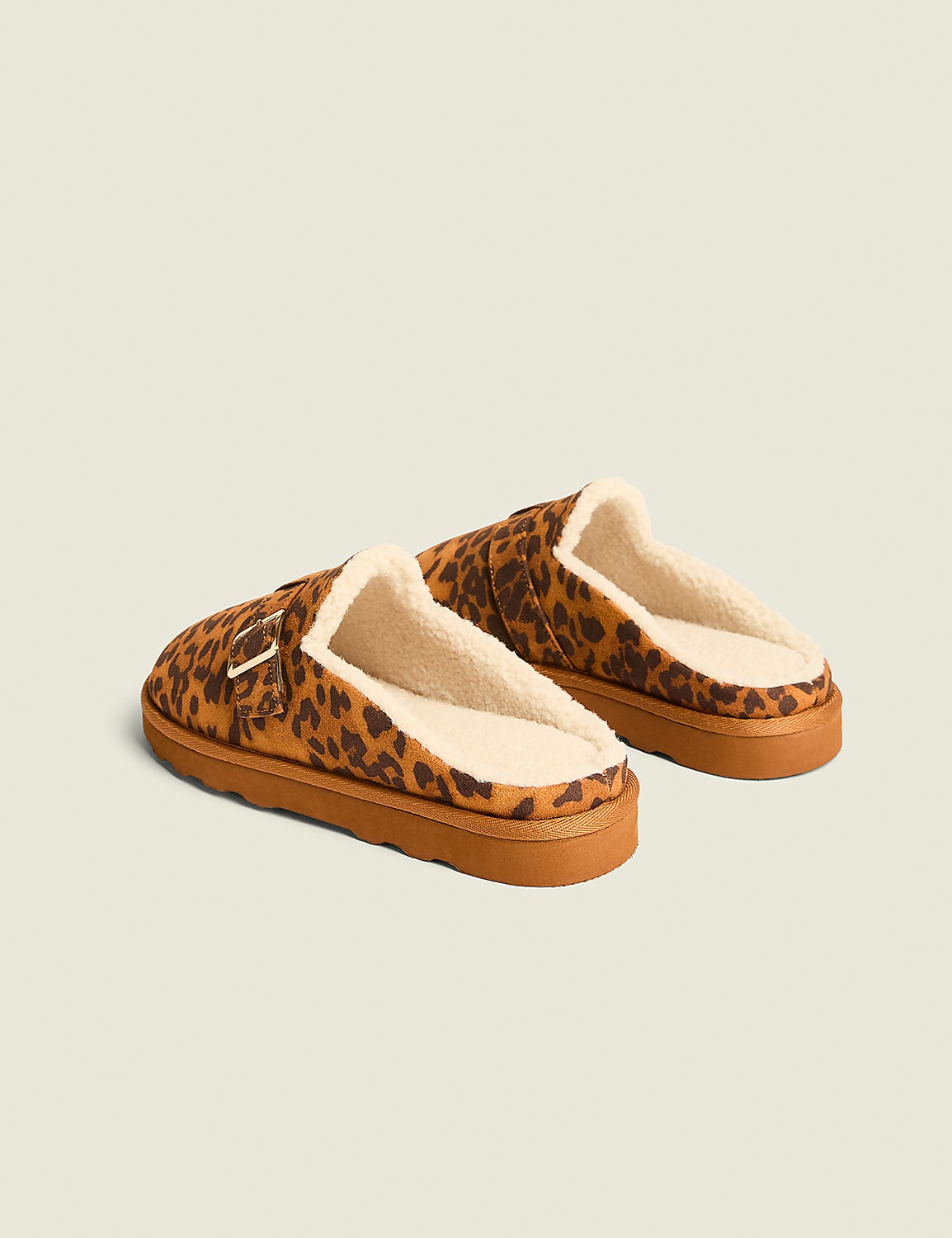 A pair of leopard-print slippers with fuzzy white lining rests on a plain, light brown background. Product Image 2
