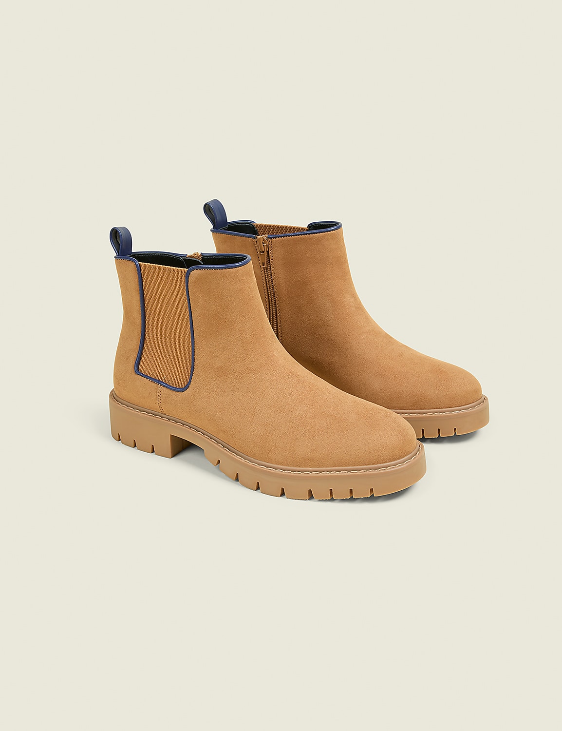 A pair of tan suede Chelsea boots with dark blue trim and thick lug soles are displayed against a plain, light gray background. Product Image 1