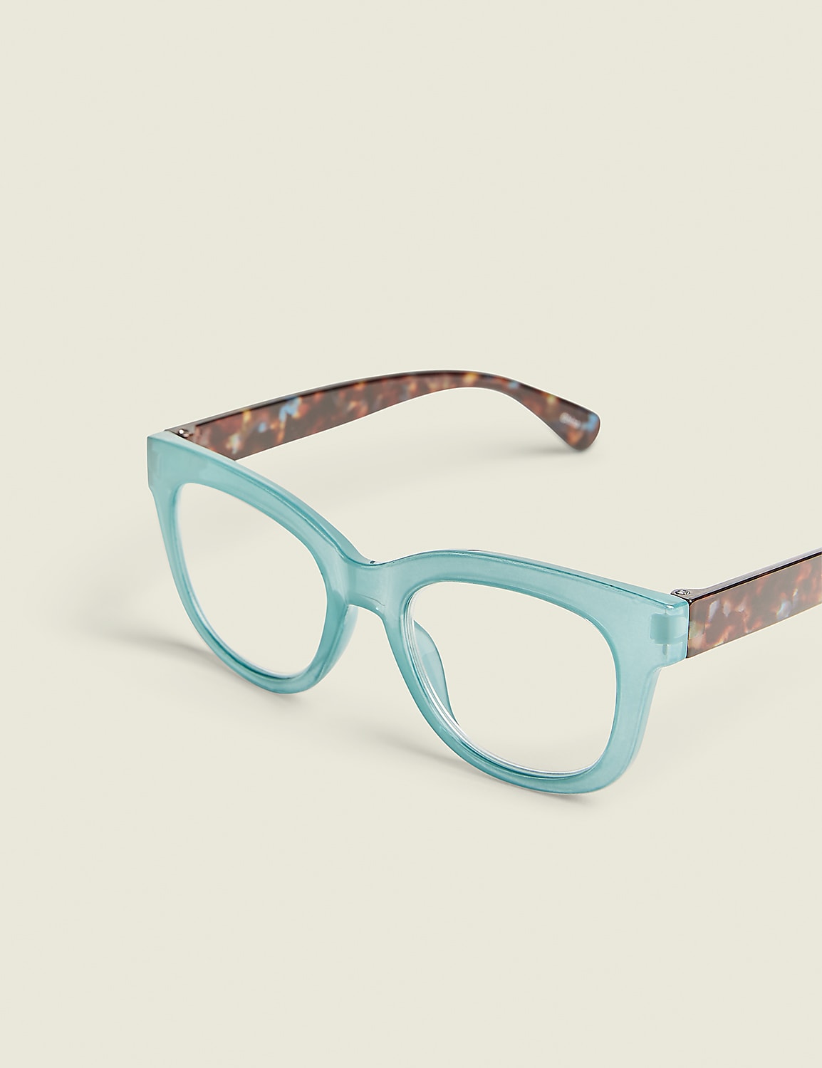 A pair of light blue cat-eye glasses with tortoiseshell temples rests on a plain, light-colored background. Product Image 1