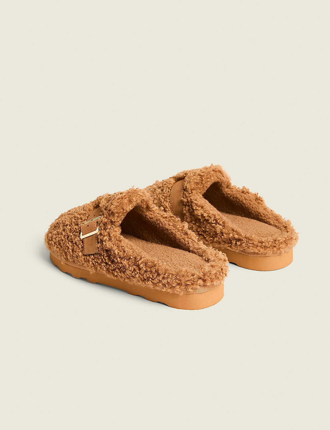 A pair of fuzzy brown slippers with a buckle detail rests on a plain, light-colored background. Product Image 2