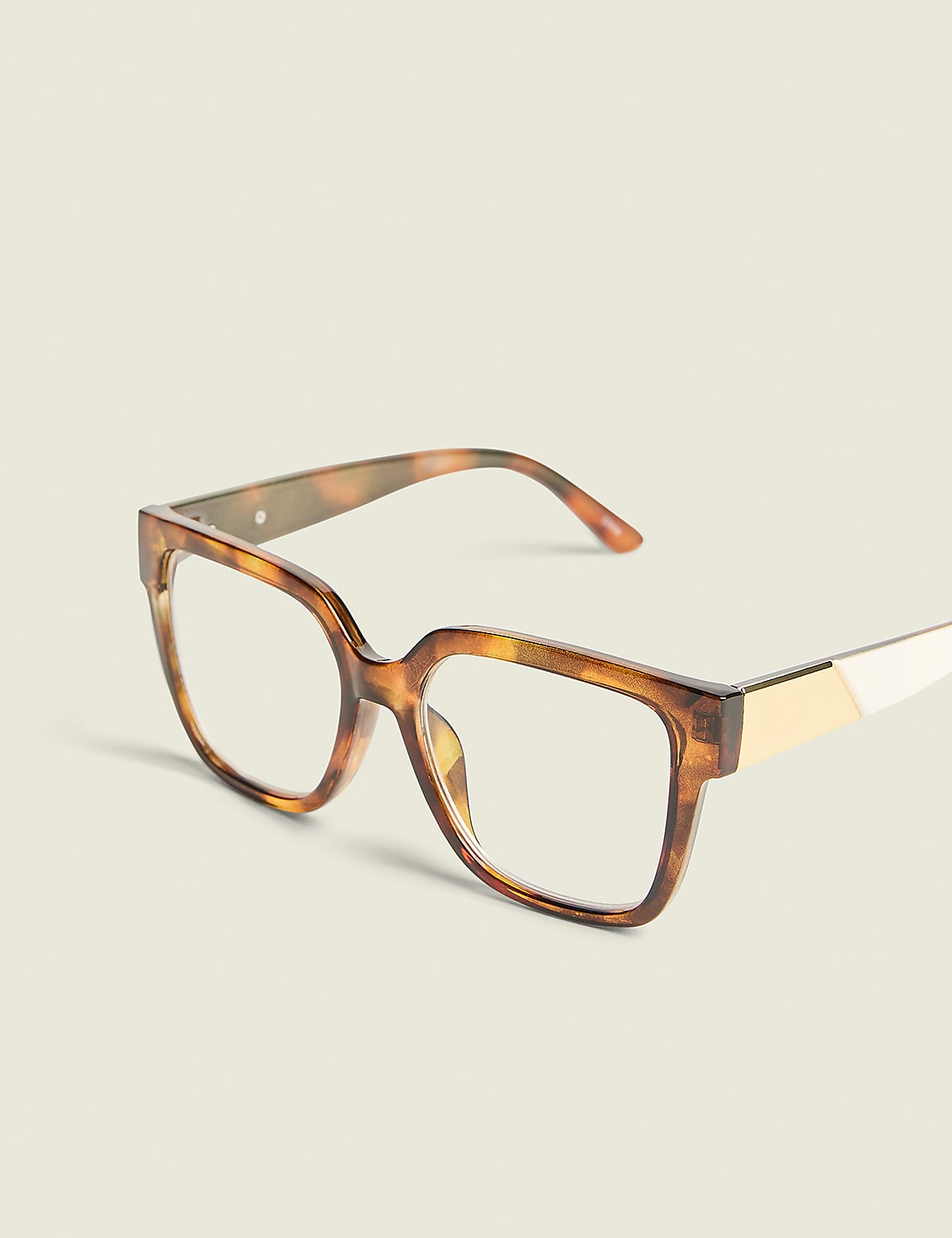 Tortoiseshell square-framed glasses with gold accents rest on a plain, light-colored surface against a soft, off-white background. Product Image 1