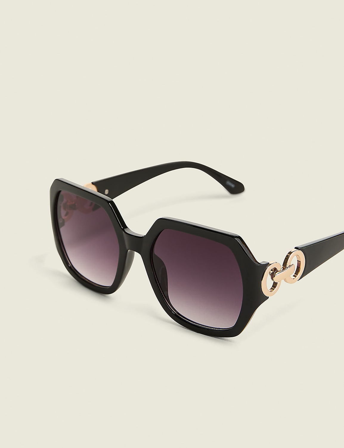 Black hexagonal sunglasses with gold chain accents rest on a plain, light-colored background. Product Image 1