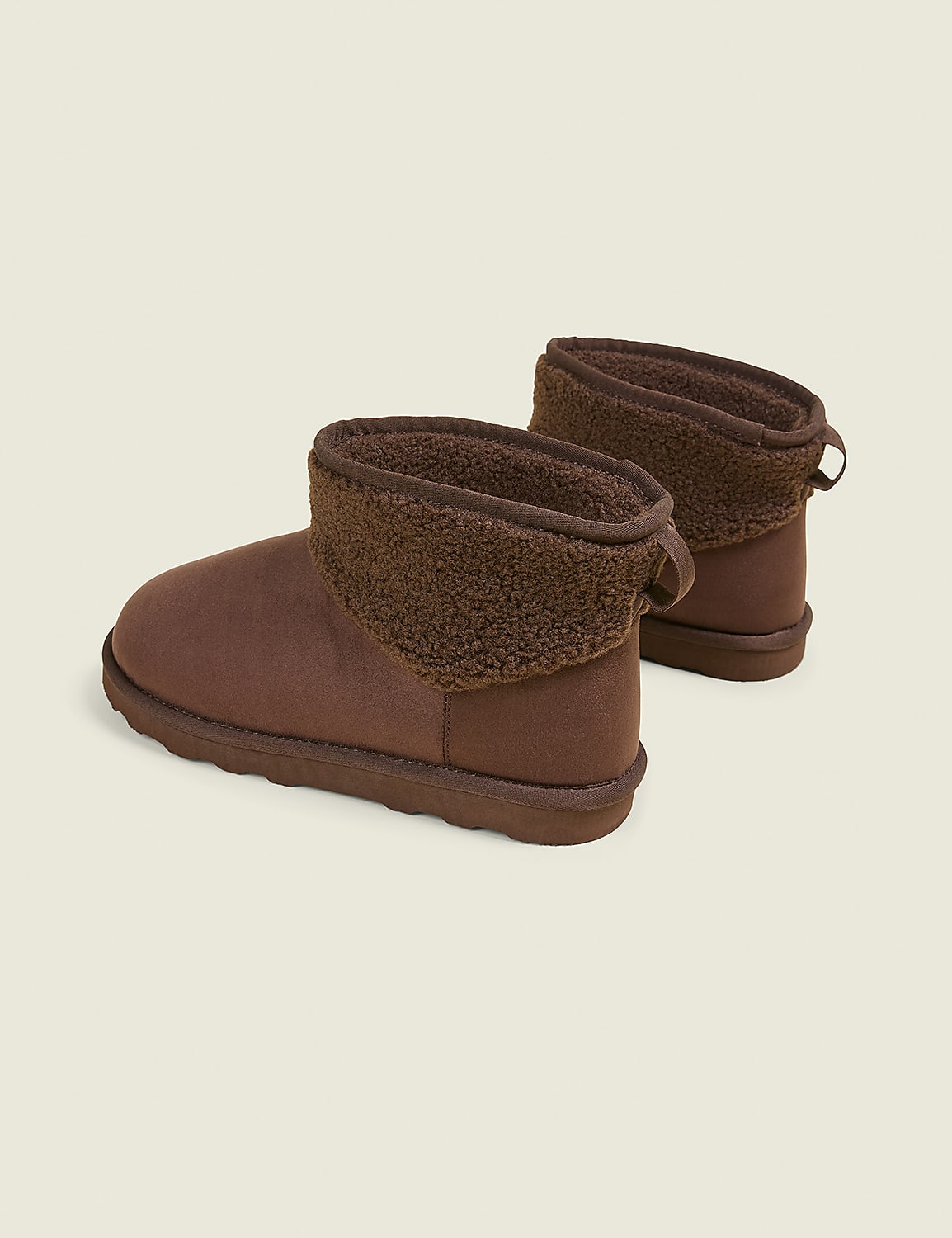 A pair of brown, fuzzy-lined ankle boots rests on a plain, light brown background. Product Image 2