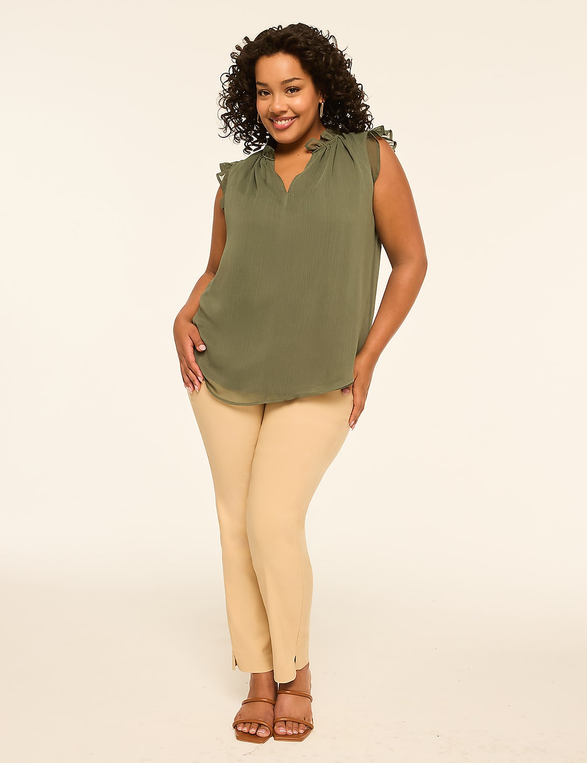 A smiling woman in a green top and tan pants stands against a plain, light-colored background. Product Image 3