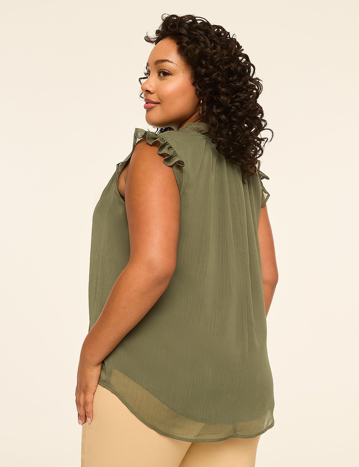 A woman in a green ruffled top stands against a plain, light-colored background. Product Image 2