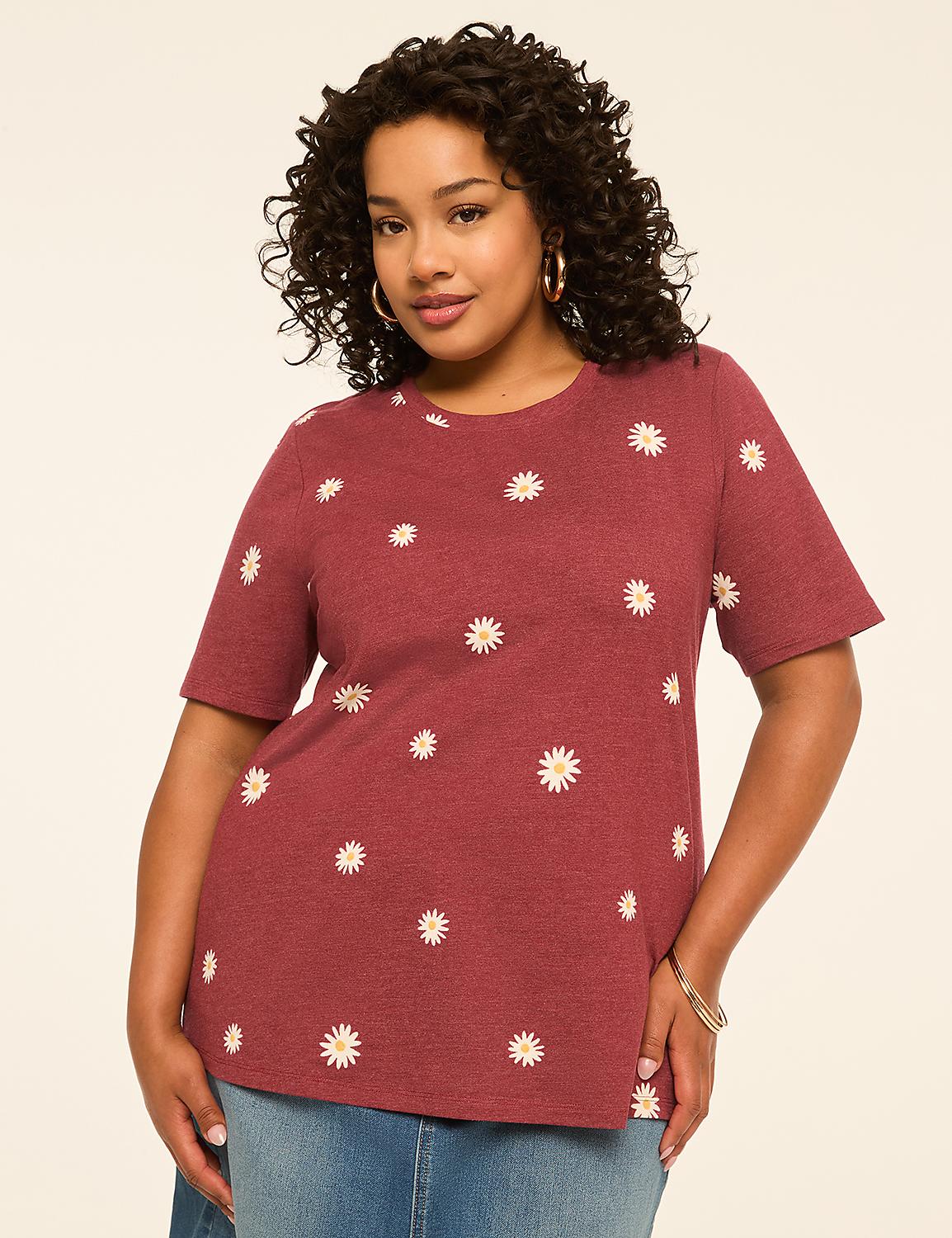 A woman with curly dark hair and hoop earrings poses in a maroon t-shirt with a daisy print against a plain, light-colored background. Product Image 1