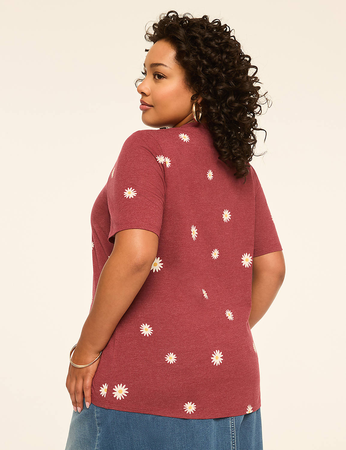 A woman in a maroon t-shirt with a daisy print stands against a plain, light-colored background. Product Image 2