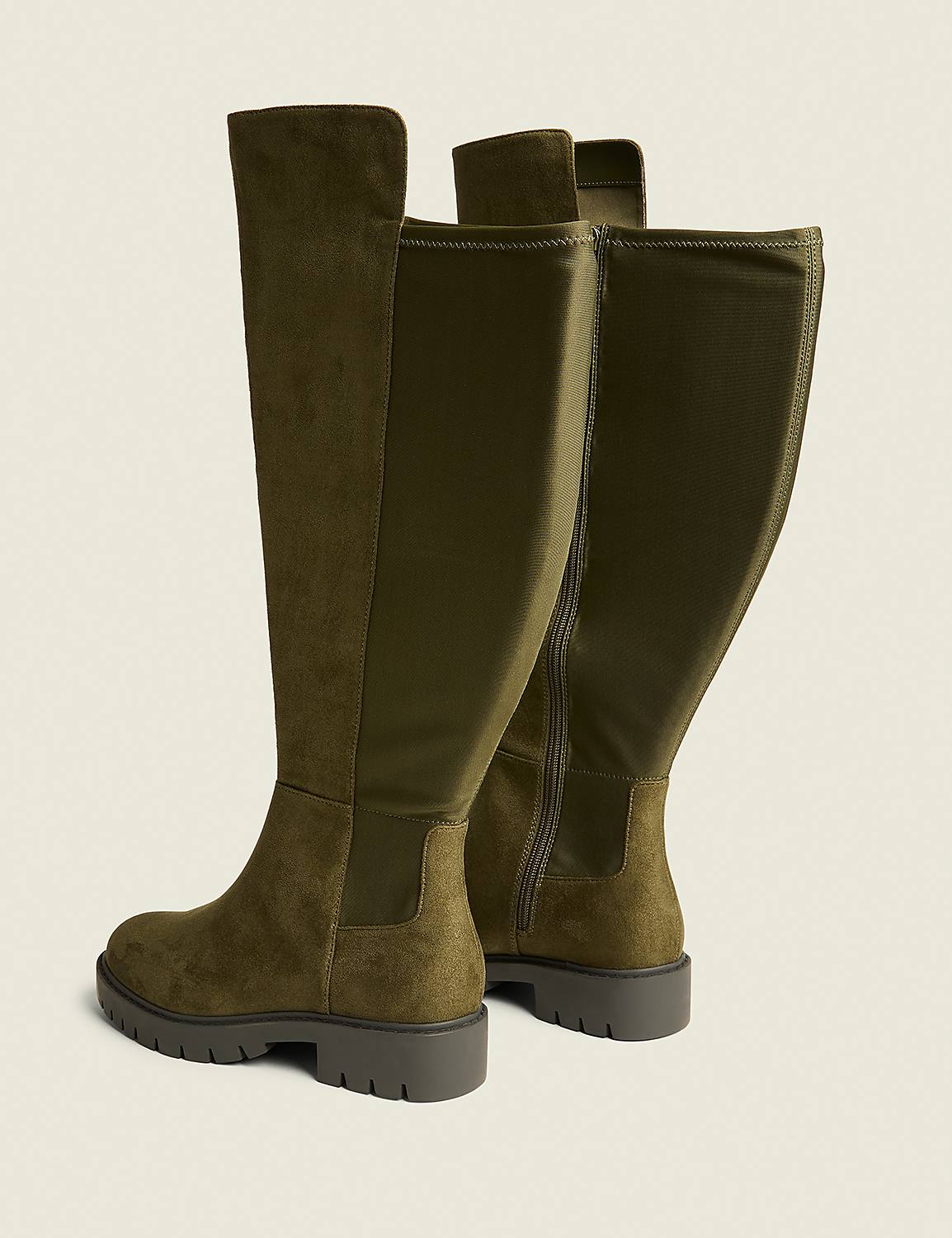 A pair of olive green, knee-high boots with a suede and fabric upper and a thick lug sole stand against a plain, light gray background. Product Image 2