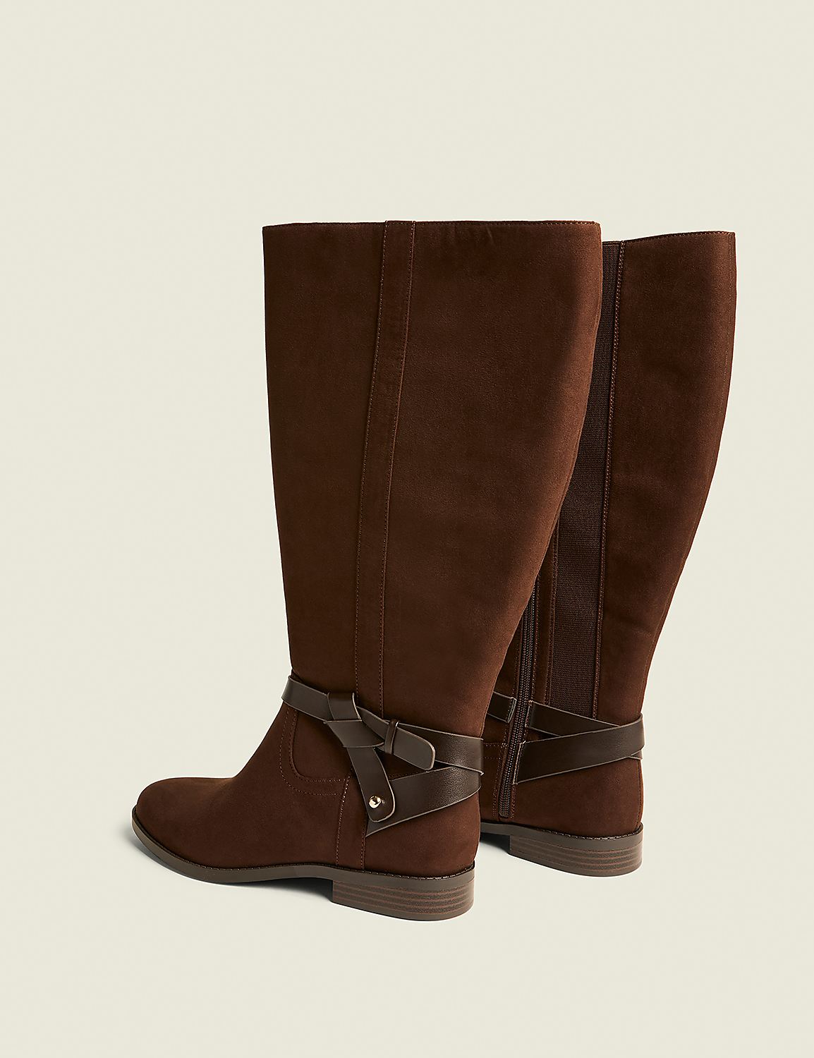 A pair of brown suede knee-high boots with a decorative strap and buckle are displayed against a plain, light brown background. Product Image 2