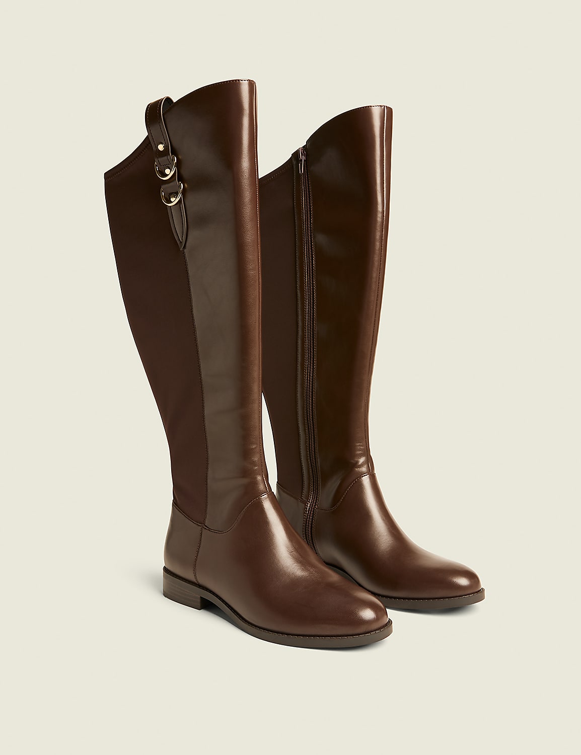 A pair of brown leather knee-high boots with elasticated panels and gold buckle details stand on a plain, light-colored background. Product Image 1
