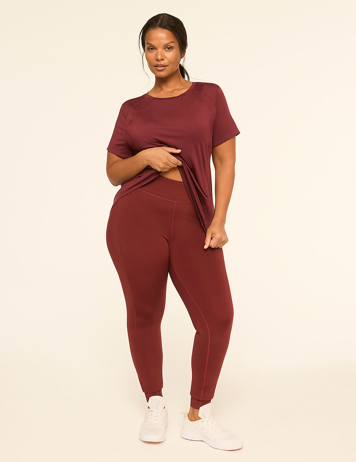 A woman in a maroon t-shirt and leggings stands against a plain, light-colored background. Product Image 3