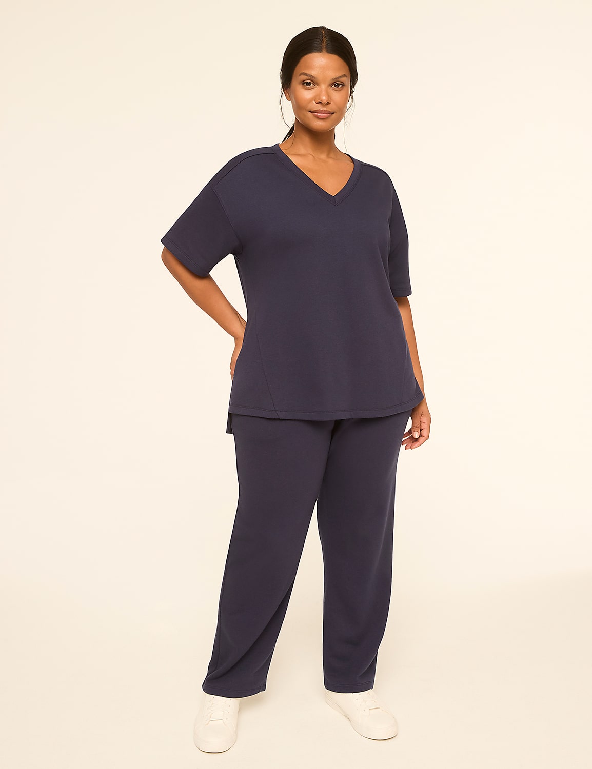 A woman in a navy blue v-neck top and matching pants stands against a plain, light-colored background. Product Image 3