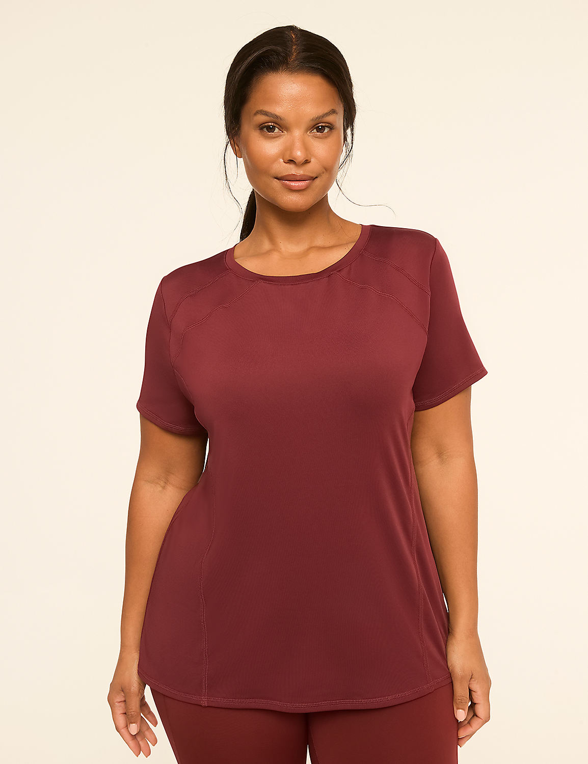 A woman in a maroon t-shirt and leggings stands against a plain, light-colored background. Product Image 1