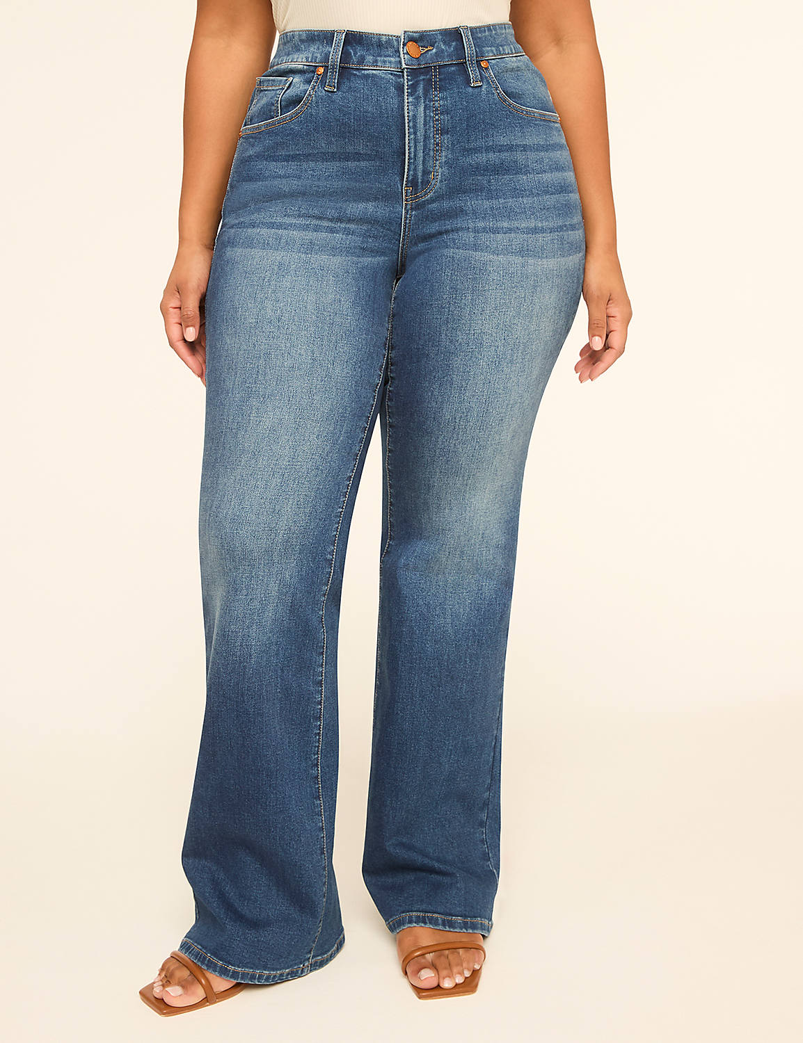 A person stands in the foreground wearing flared blue jeans and sandals, against a plain, light-colored background. Product Image 1