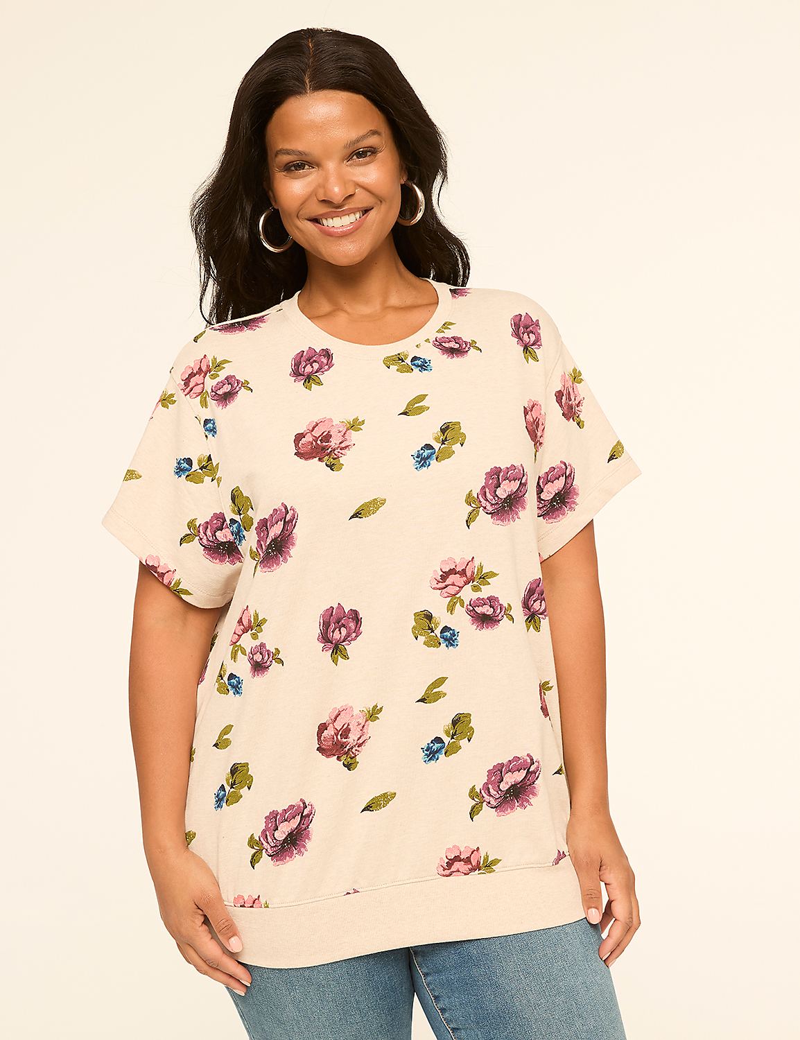 A smiling woman in a floral top stands against a plain, light-colored background. Product Image 1