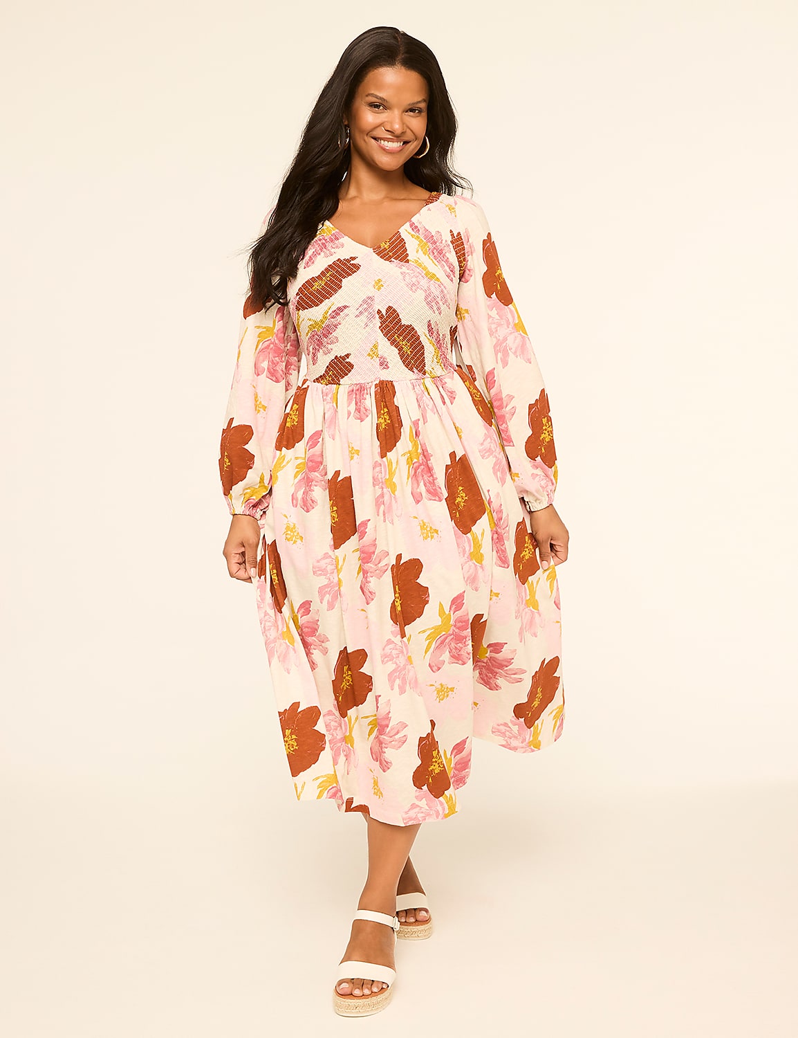 A woman in a floral dress stands against a plain, light-colored background. Product Image 1