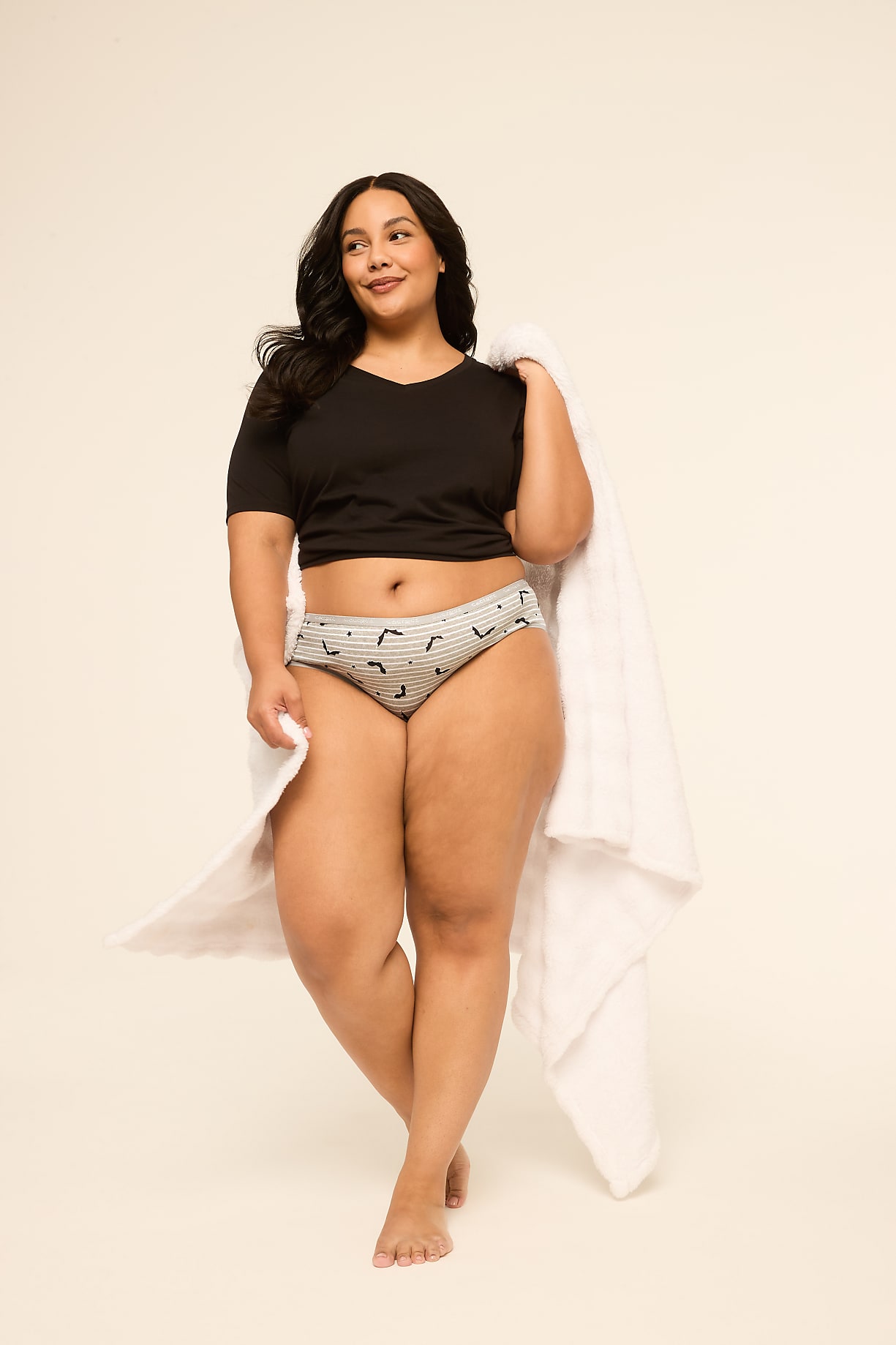 A woman in a black crop top and patterned underwear stands with a white towel draped over her shoulder against a plain, light background. Product Image 3