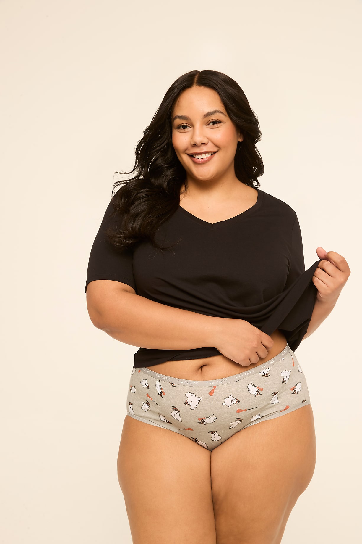 A smiling woman in a black t-shirt and patterned underwear stands against a plain, light-colored background. Product Image 6