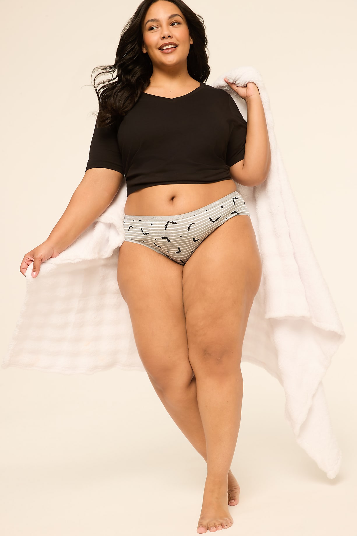 A woman in a black crop top and patterned underwear stands with a white towel draped over her shoulder against a plain, light-colored background. Product Image 5