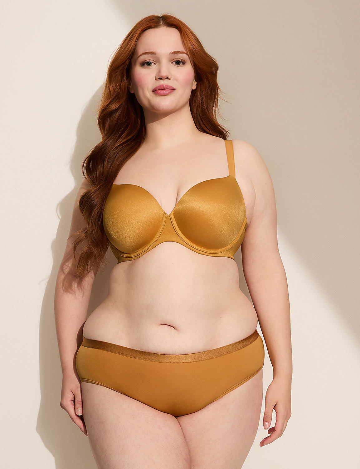A woman with red hair stands in a golden bra and underwear against a plain, light-colored background with soft shadows. Product Image 3
