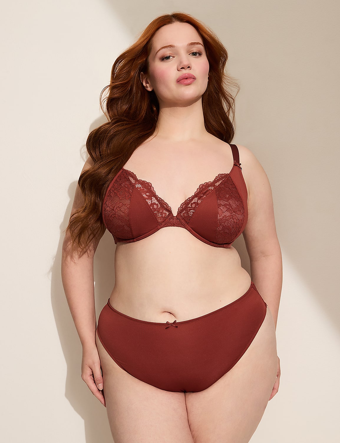 A woman with red hair poses in a rust-colored bra and underwear against a plain, softly lit background. Product Image 4