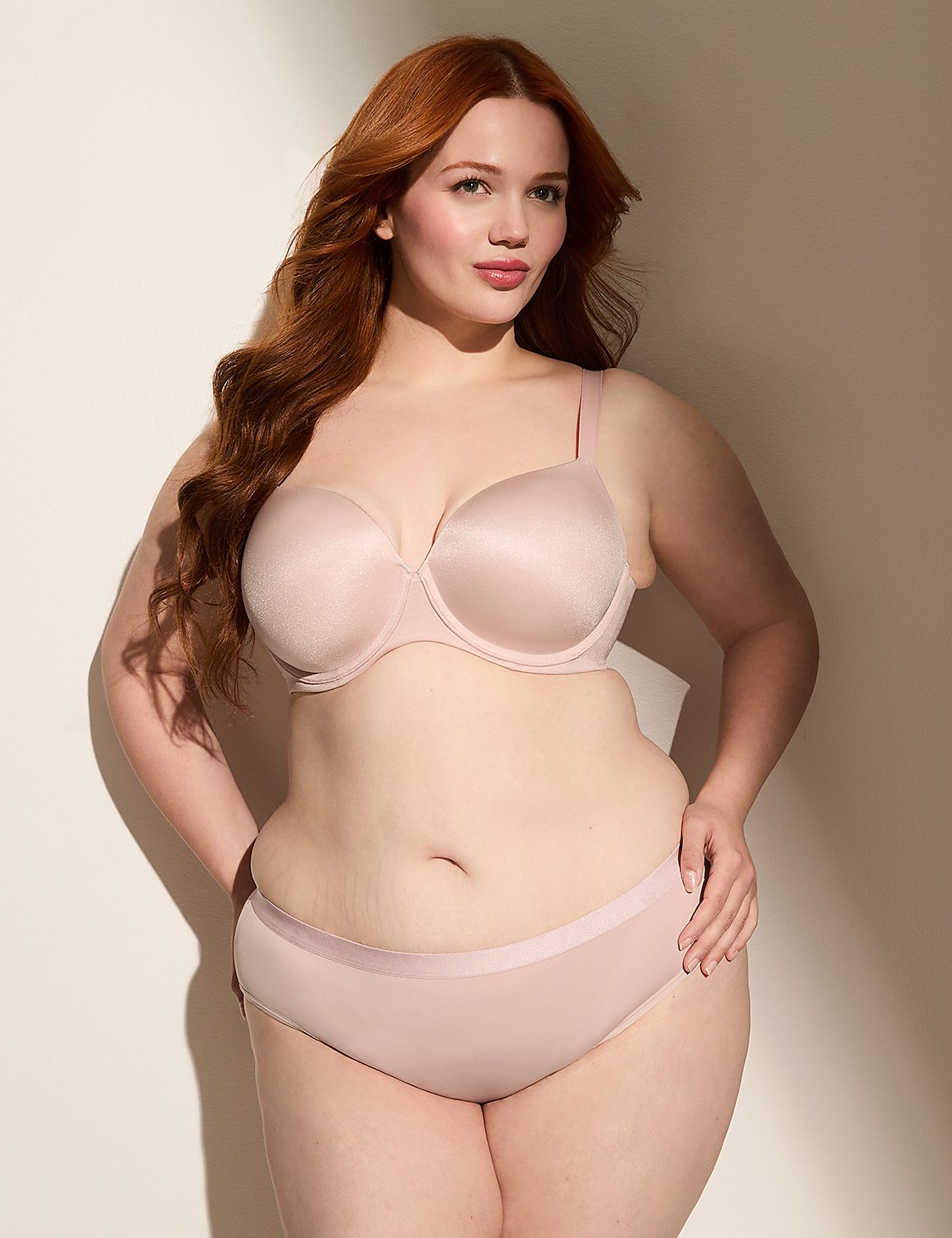 A woman with long red hair poses in a light pink bra and matching underwear against a plain, softly lit background. Product Image 4