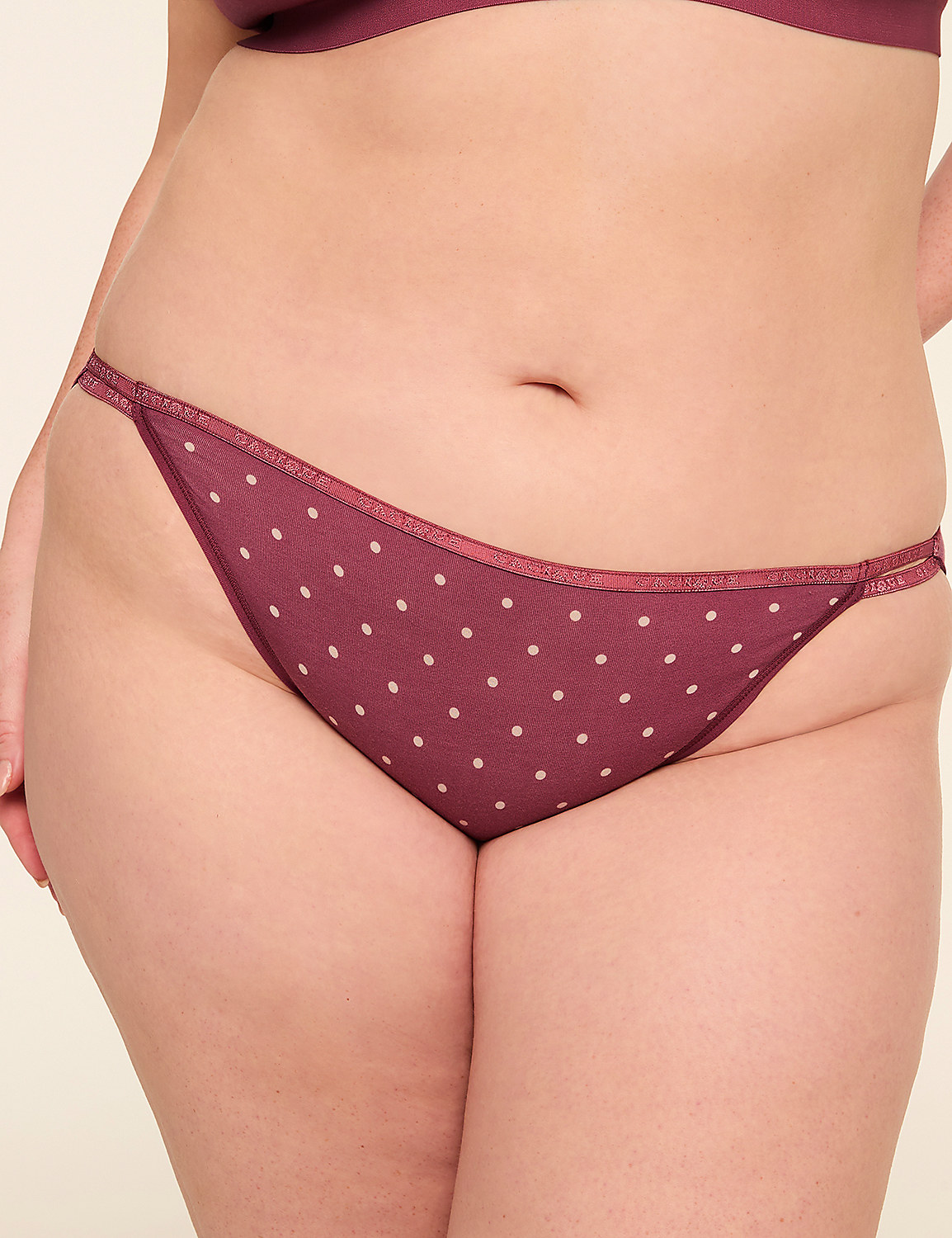 A close-up of a person's lower torso wearing burgundy polka dot underwear against a plain background. Product Image 1