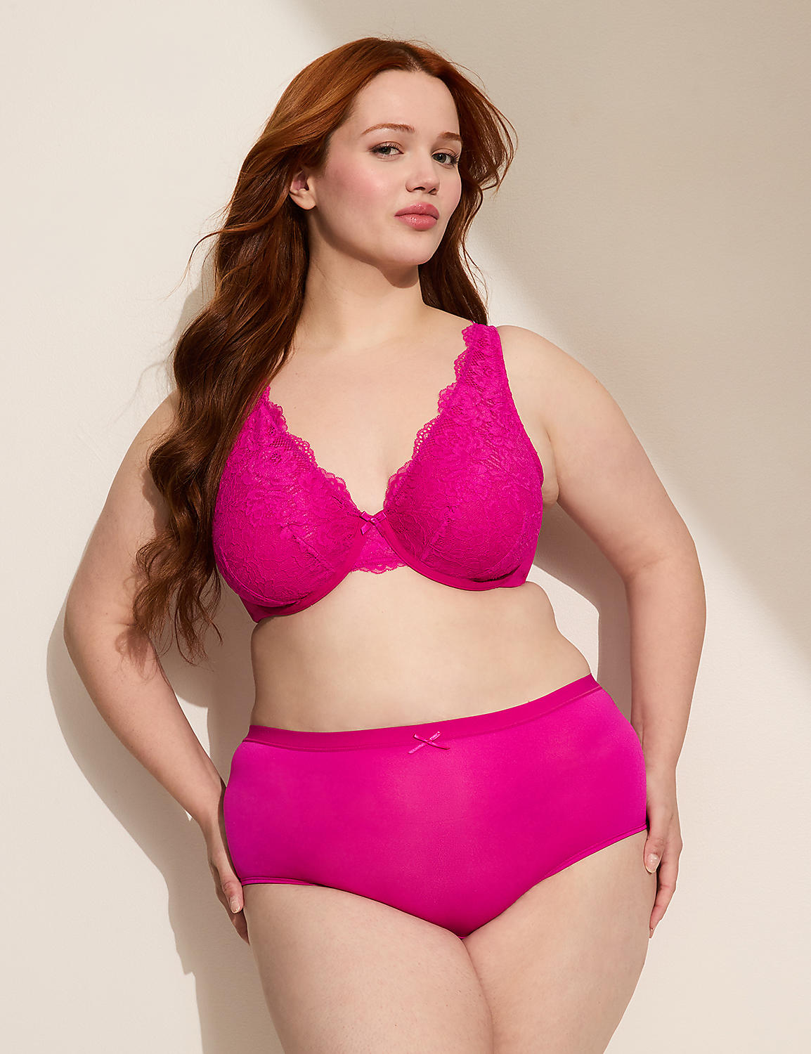 A woman with long red hair poses in a bright pink lace bra and matching high-waisted underwear against a plain, light-colored background. Product Image 3