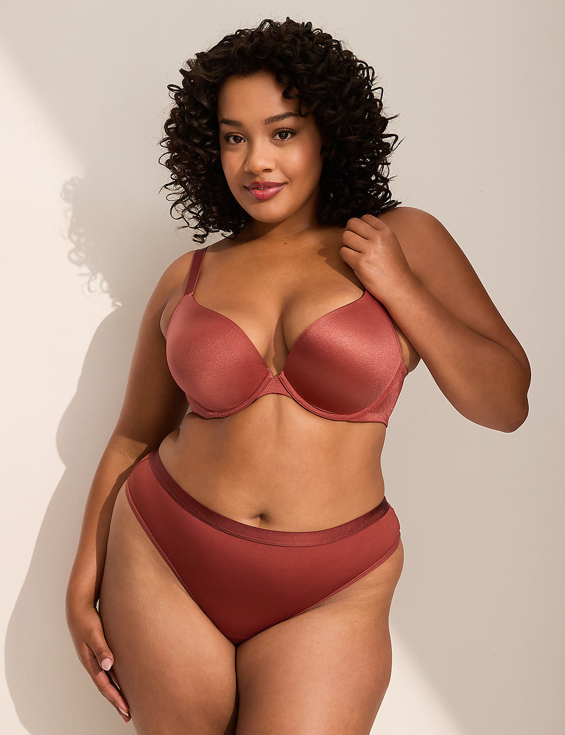A woman with curly dark hair poses in a rose-colored bra and underwear against a plain, light-colored background with soft shadows. Product Image 3