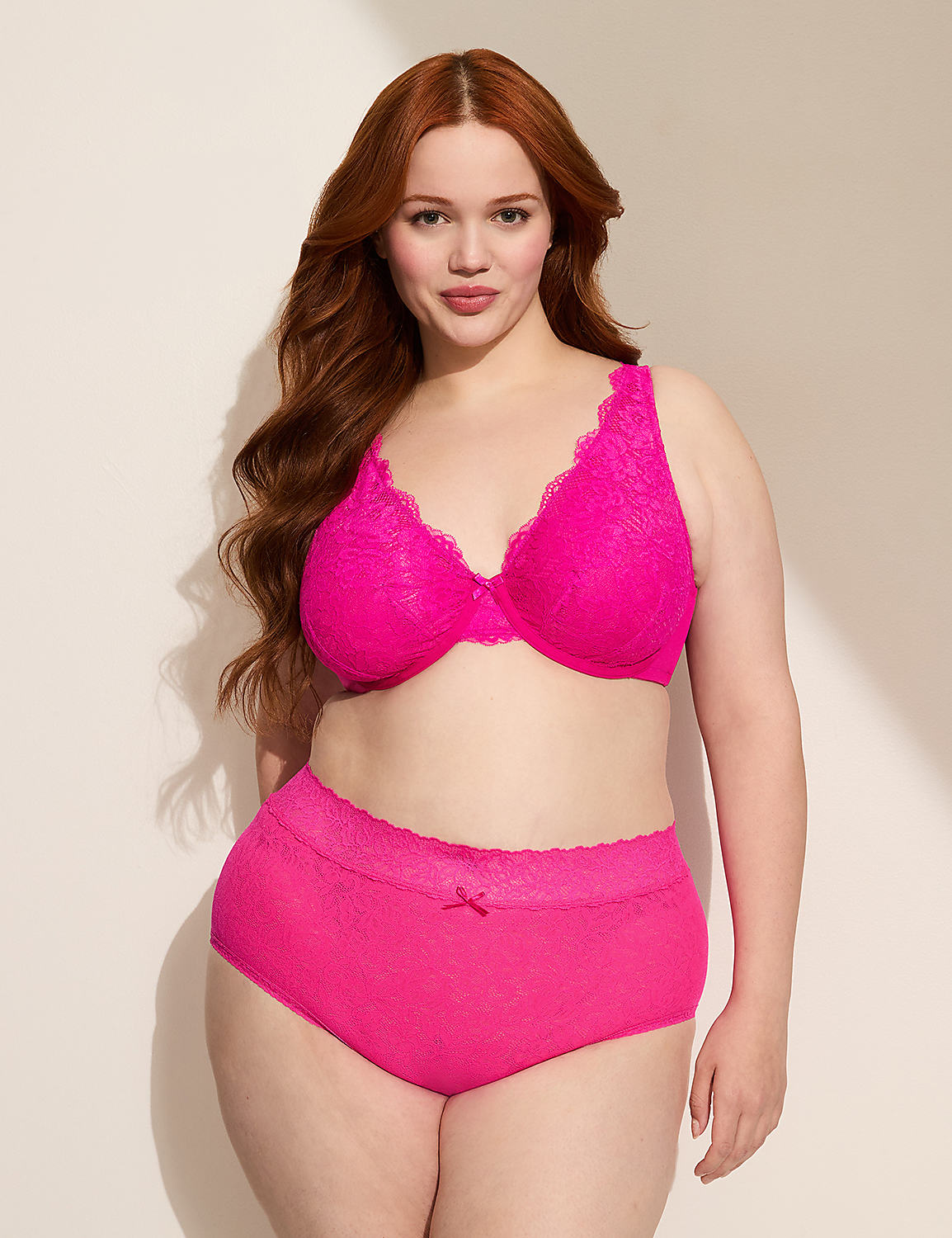 A woman with long, wavy red hair poses in a bright pink lace bra and matching high-waisted briefs against a plain, light-colored background. Product Image 3
