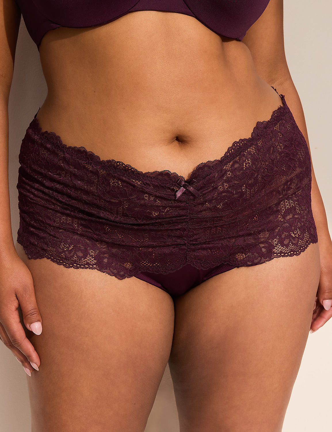 A person in dark purple lace underwear stands against a plain, light-colored background. Product Image 1
