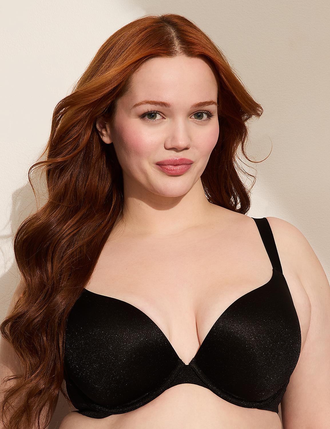 A woman with long, wavy red hair smiles gently in the foreground, wearing a black bra against a plain, light-colored background. Product Image 1