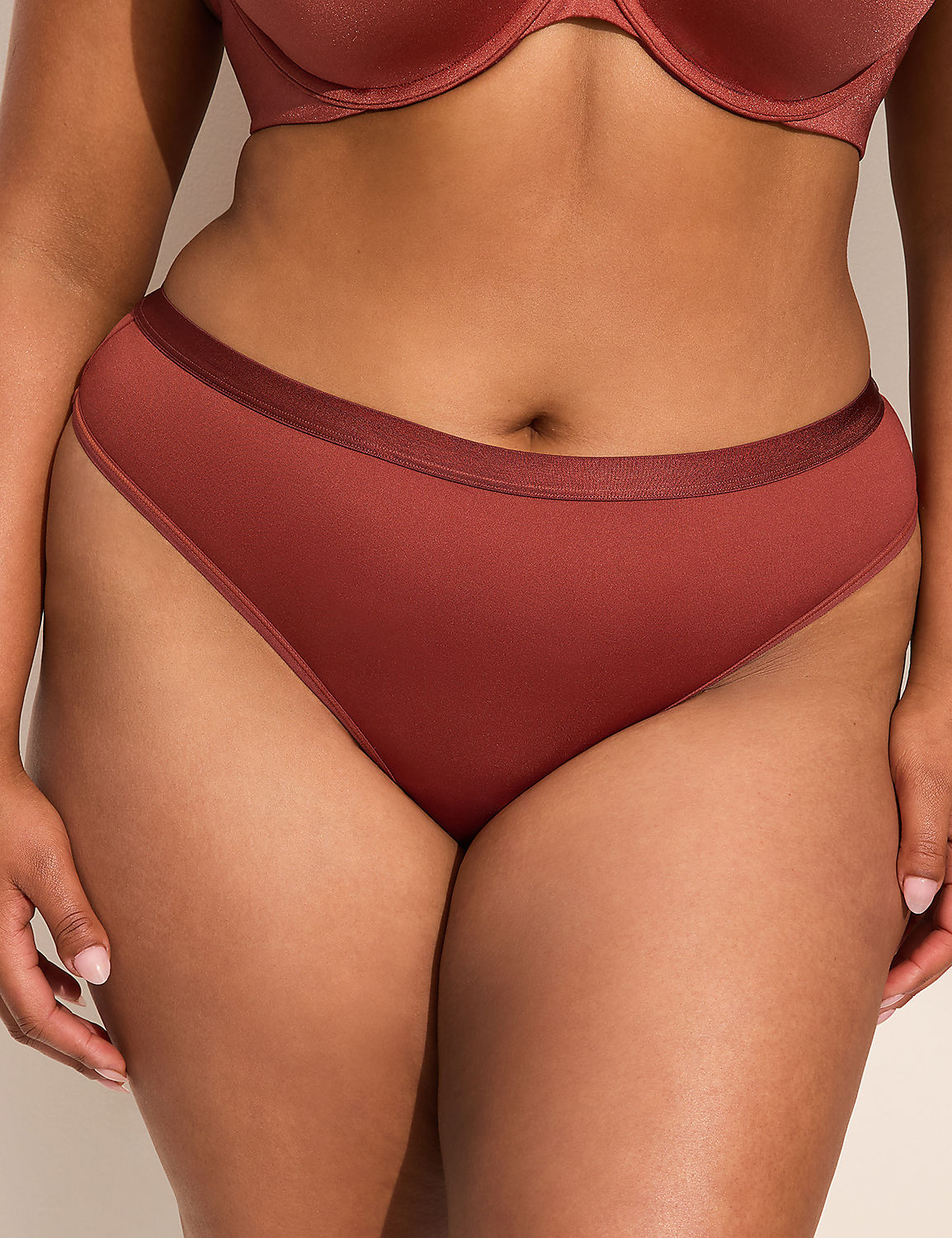 A person in a rust-colored bra and matching high-cut underwear stands against a plain, light-colored background. Product Image 1