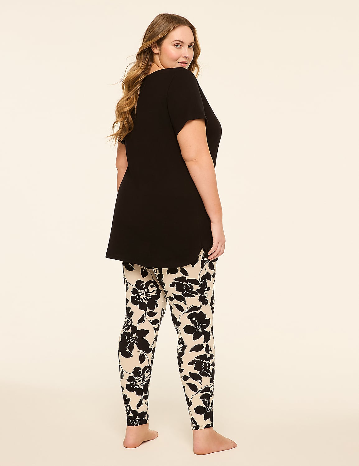 A woman in a black top and floral leggings stands against a plain, light-colored background. Product Image 2