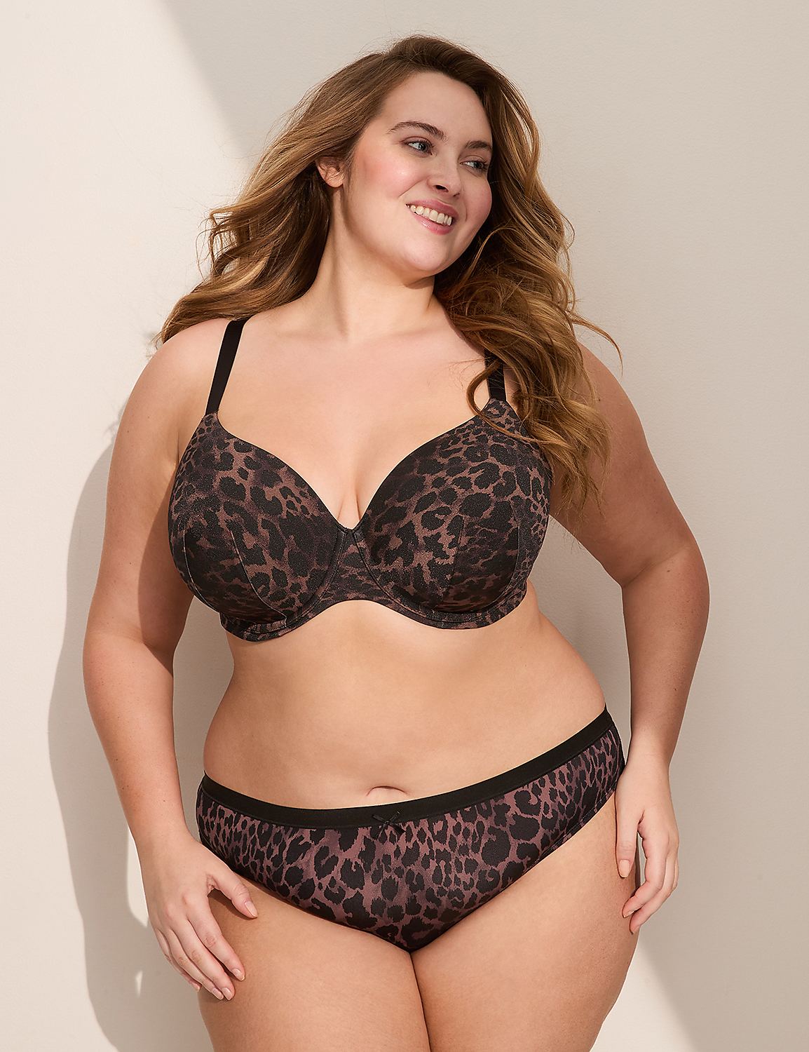 A woman in a leopard print bra and underwear smiles against a plain background with a shadow on the wall. Product Image 3