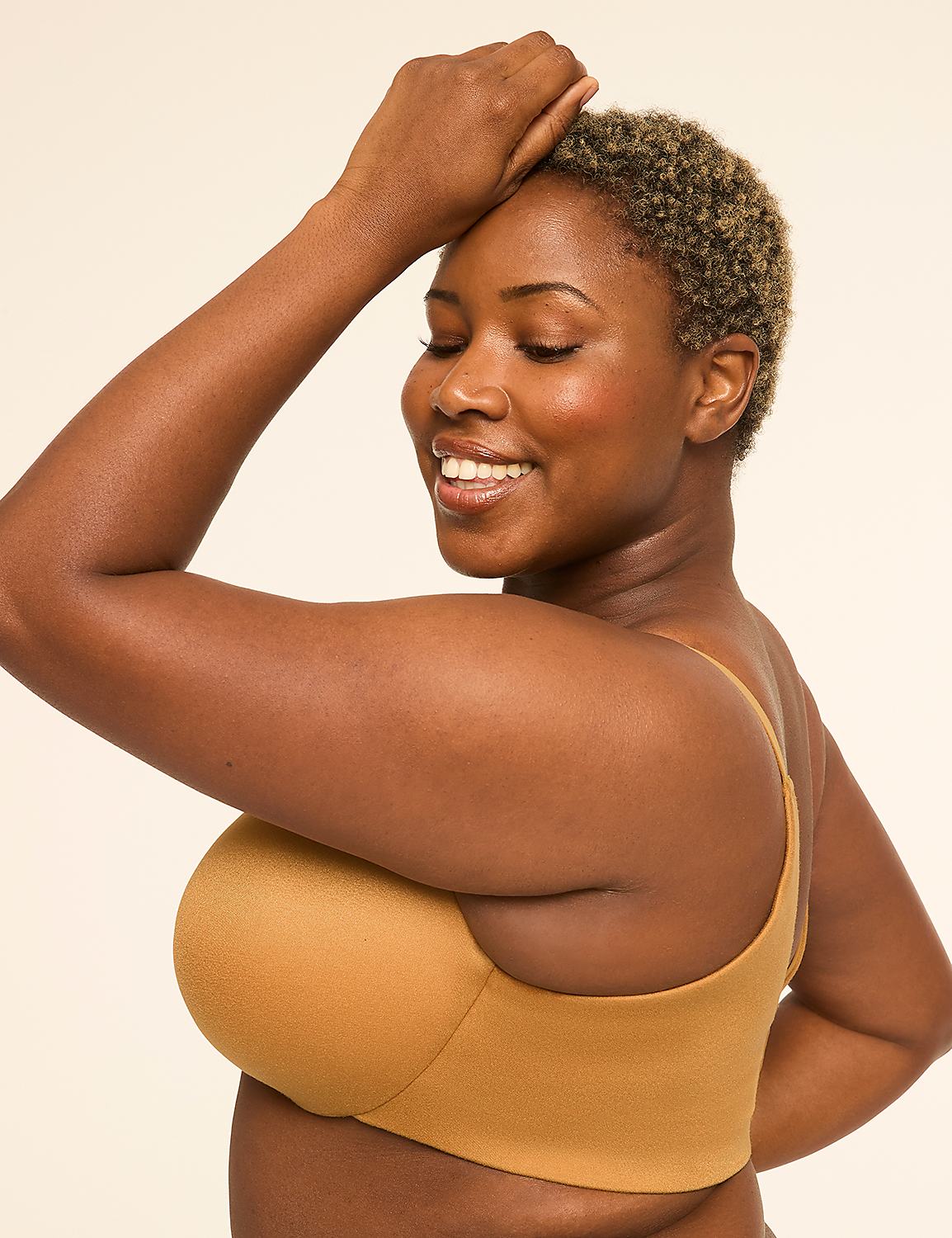 A woman with dark skin and short, curly hair smiles with her eyes closed, her arm raised behind her head, against a plain, light-colored background. Product Image 3
