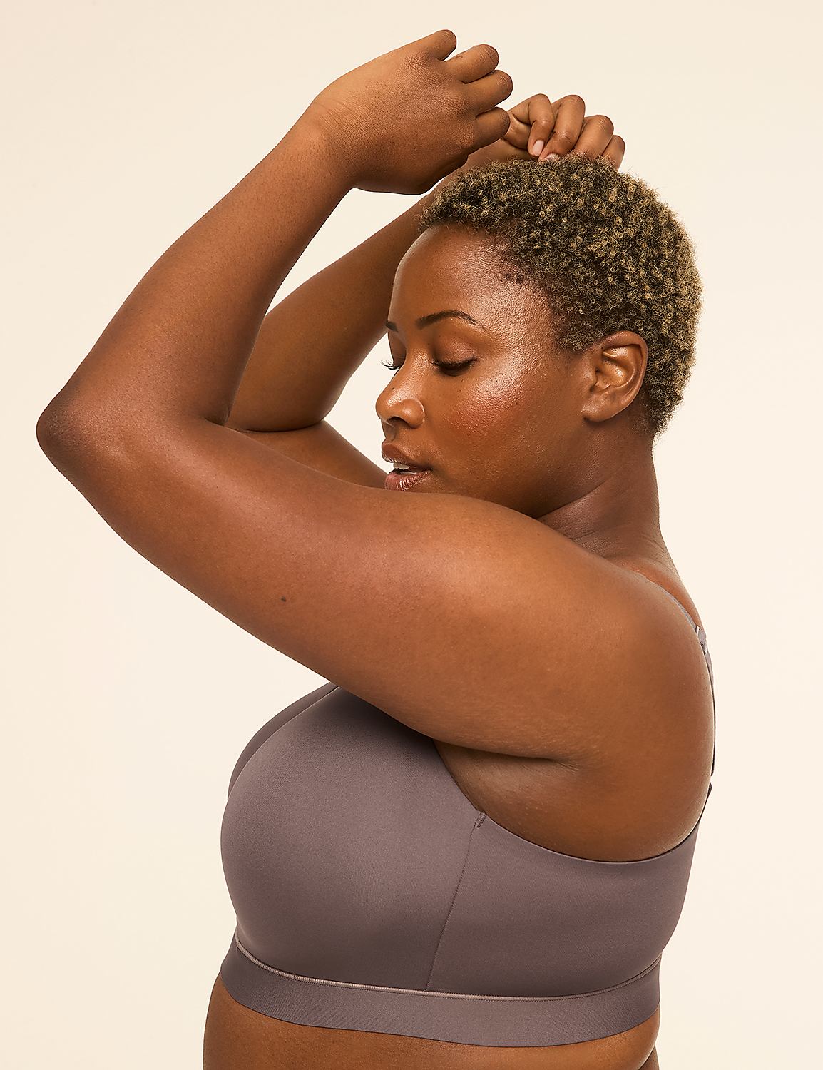 A woman with short, curly hair poses with her arms raised against a plain, light-colored background. Product Image 3