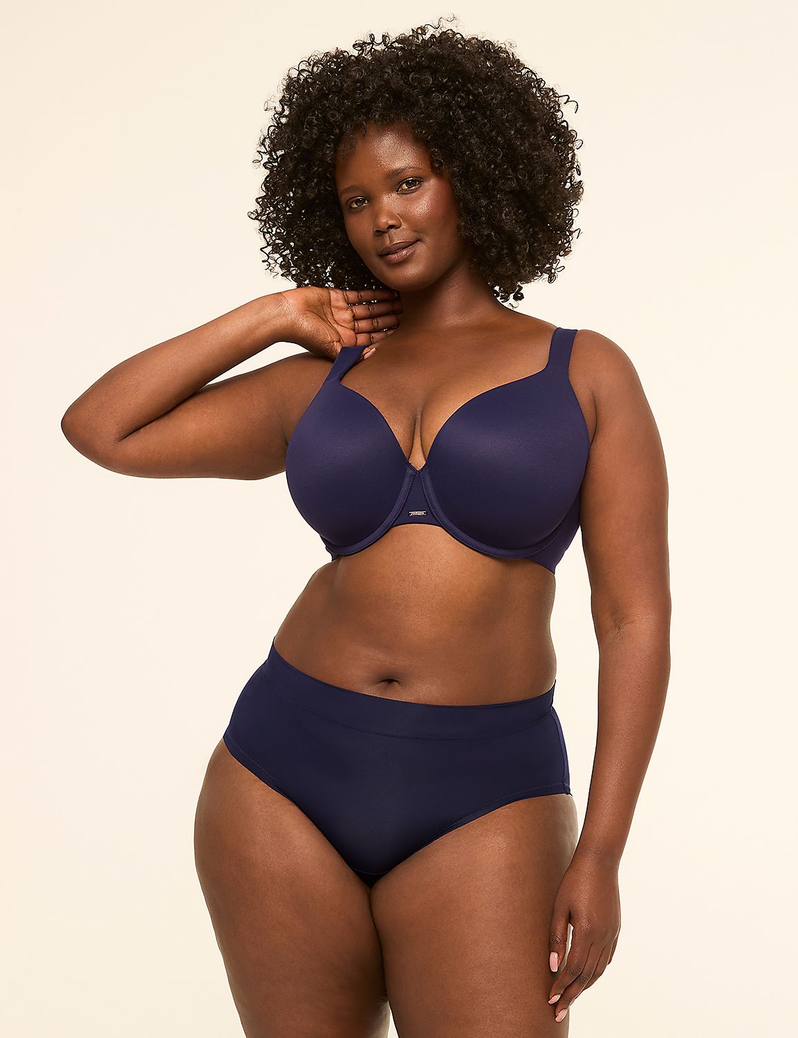 A woman with dark curly hair poses in navy blue lingerie against a plain, light-colored background. Product Image 4