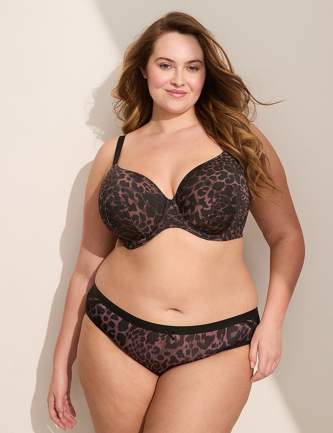 A woman in a leopard print bra and underwear stands against a plain, light-colored wall with a shadow cast on it. Product Image 3