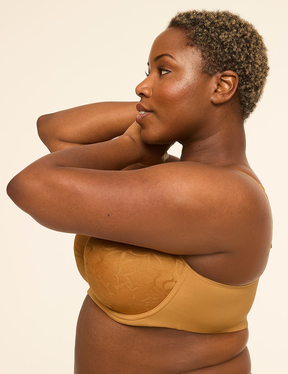 A woman in a tan bra with textured cups poses with her arms behind her head against a plain, light background. Product Image 3