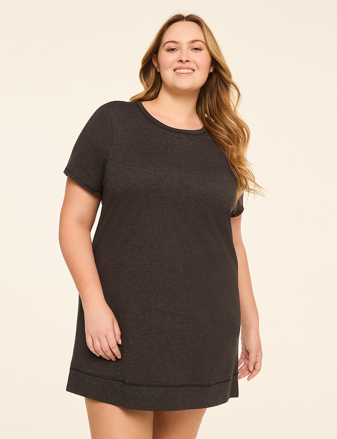 A smiling woman in a dark grey t-shirt dress stands against a plain, light beige background. Product Image 1