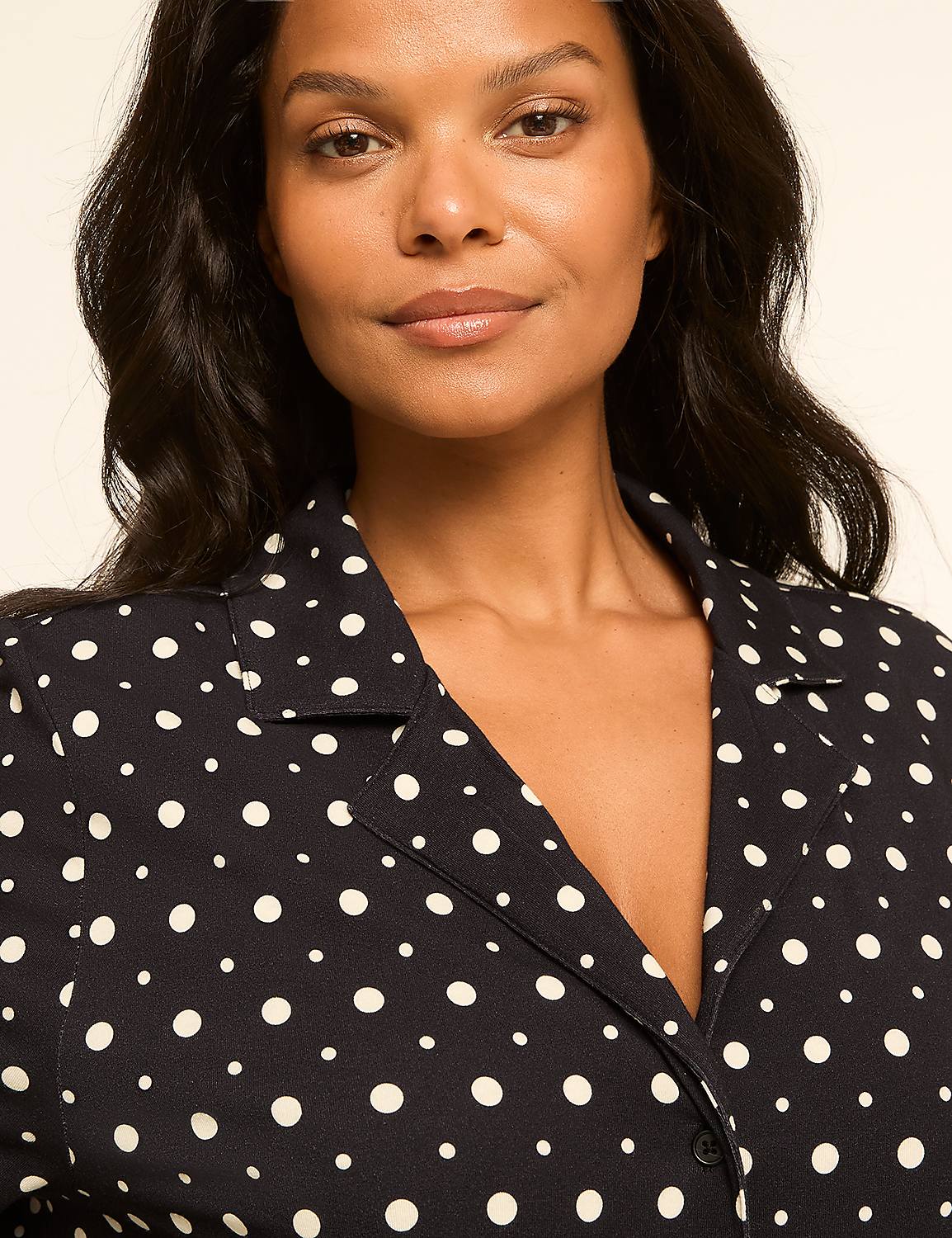 A woman with dark wavy hair and a polka dot shirt smiles gently against a plain, light background. Product Image 4