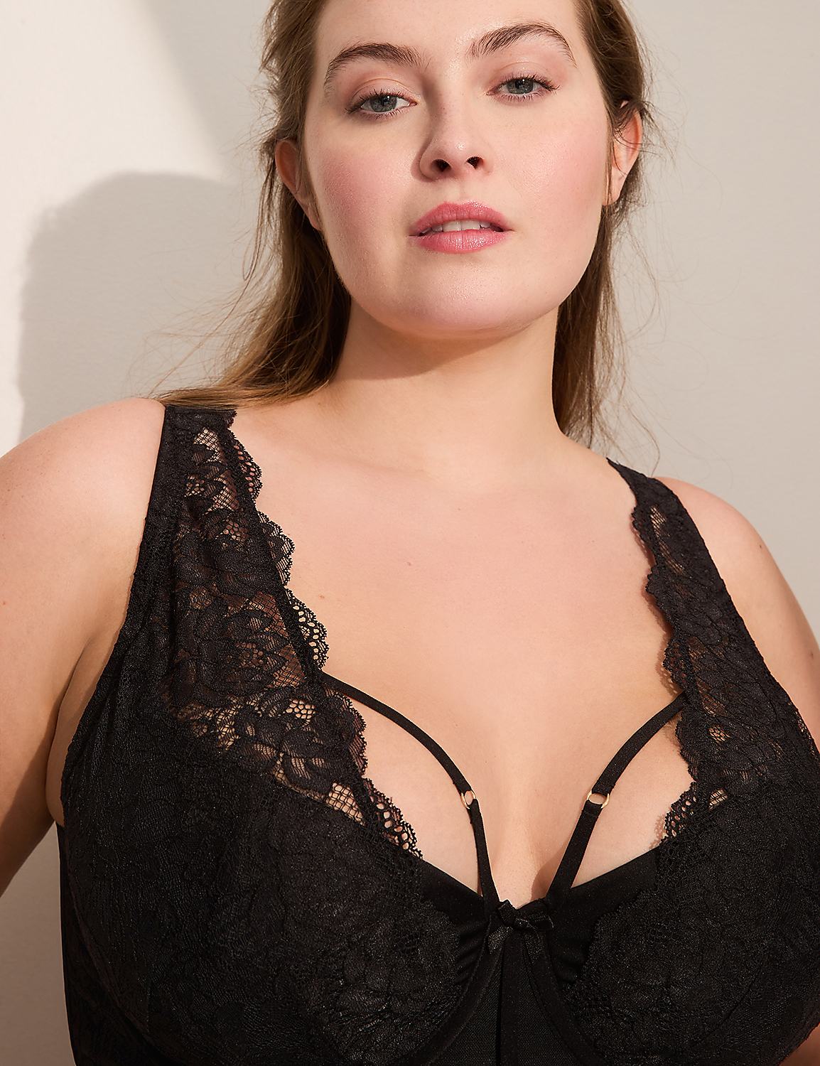 A woman with light skin and brown hair wears a black lace bra in the foreground, with a plain white wall in the background. Product Image 2