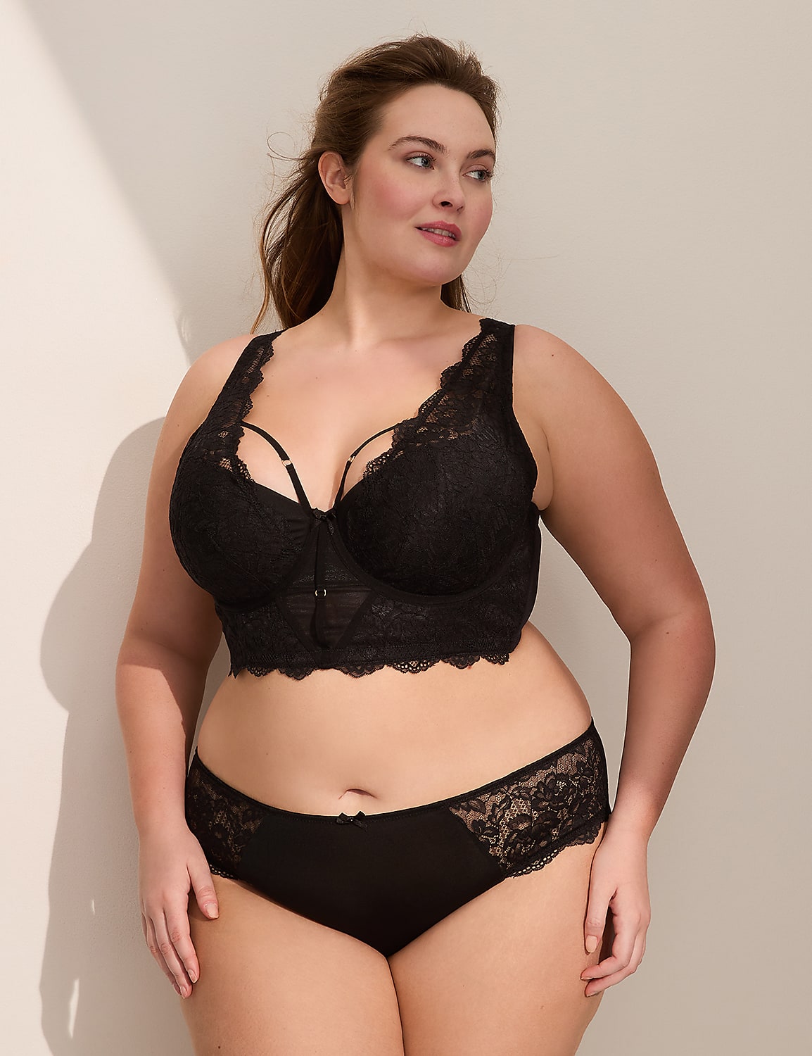A woman in black lace lingerie stands against a plain, light-colored wall with shadows. Product Image 4